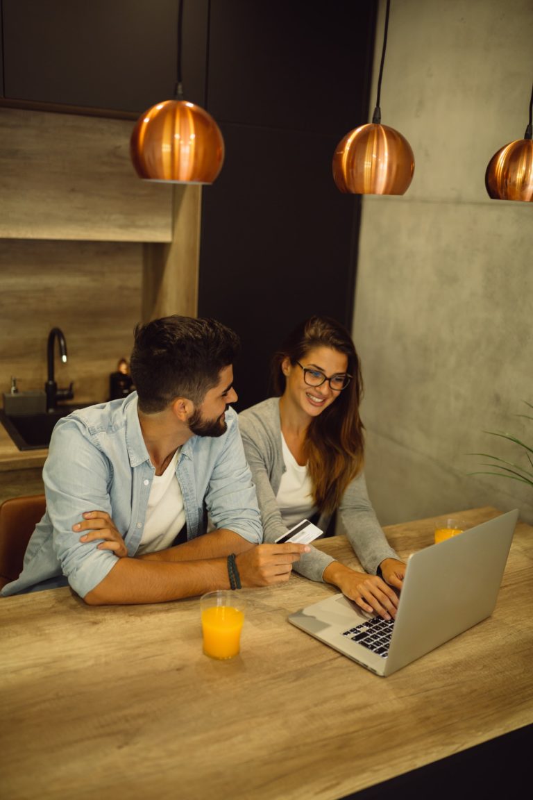 Young couple shopping online with credit card and laptop at home.